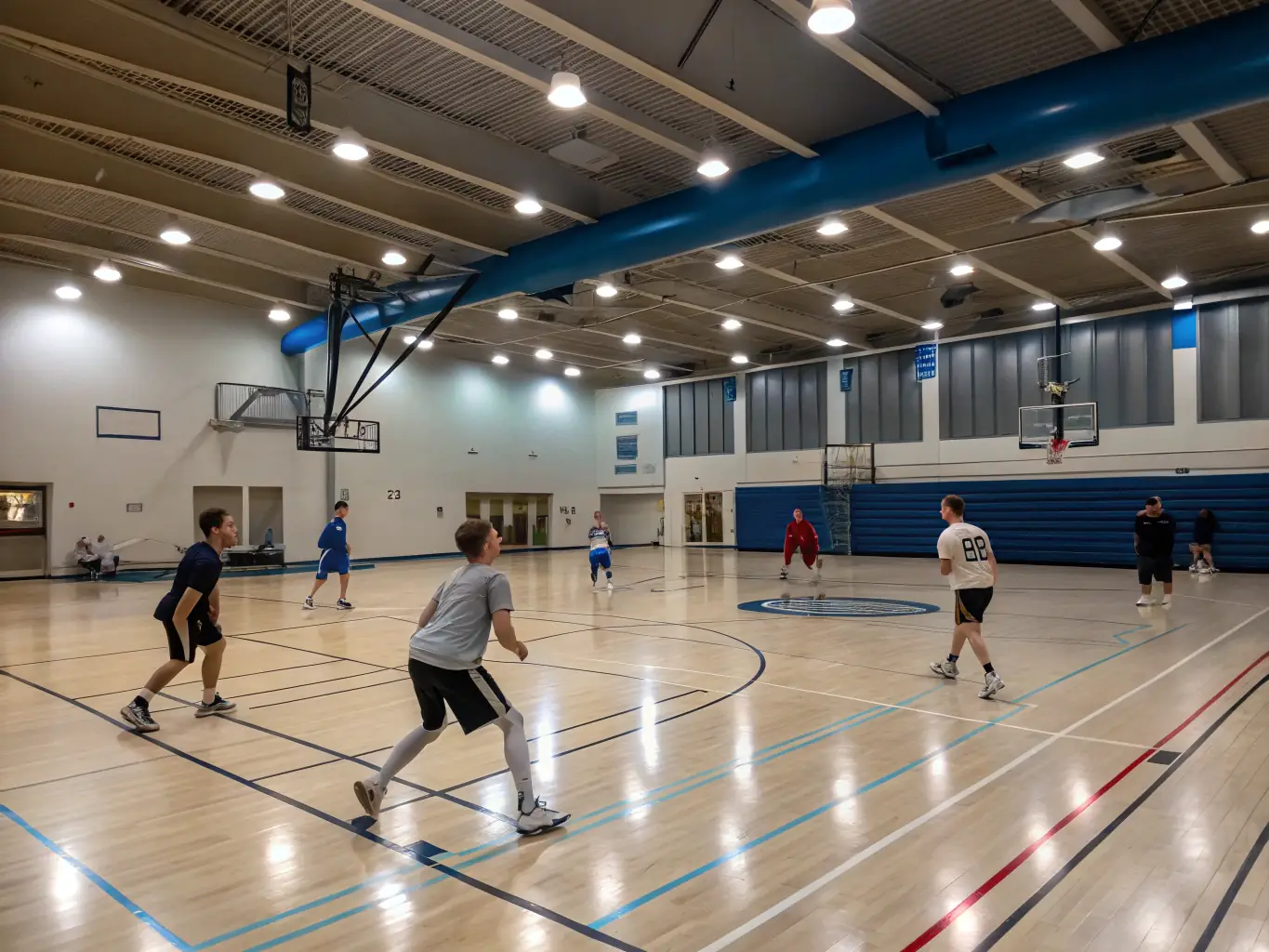 An action shot of adults playing basketball in a well-lit indoor court at Union Sportive Genlis, emphasizing fitness and competition.